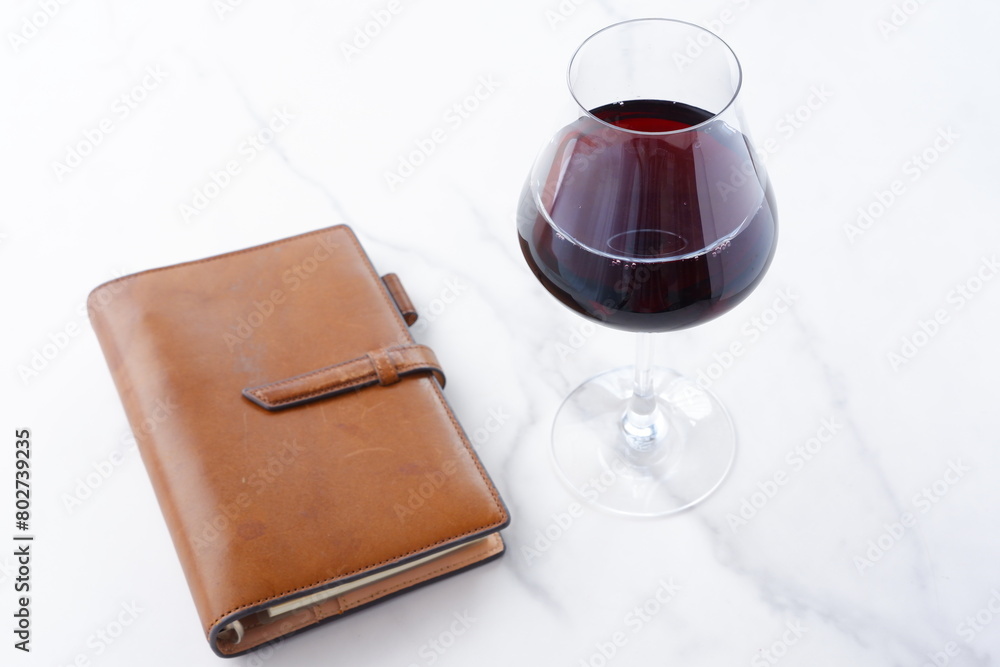 茶色の革のシステム手帳と赤ワインのグラス
