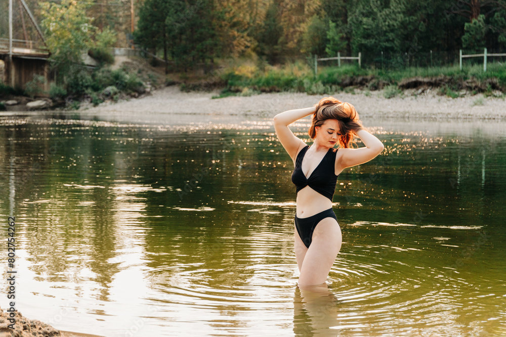 Young female in two piece black bikini standing in river water Young female in two piece black bikini standing in river water