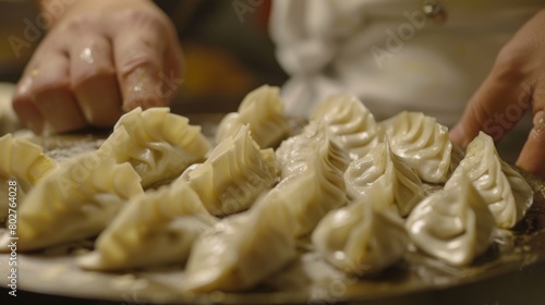 A chef meticulously arranging a plate of beautifully garnished momos, showcasing their delicate folds and vibrant colors.