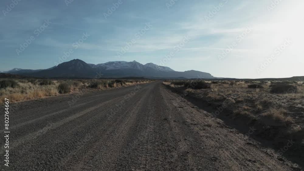 Moving along the roads of Utah, USA, the drone takes a low flight, gradually ascending to unveil the desolate and arid landscapes, painting a captivating picture of the terrain below. Moving along the roads of Utah, USA, the drone takes a low flight, gradually ascending to unveil the desolate and arid landscapes, painting a captivating picture of the terrain below.