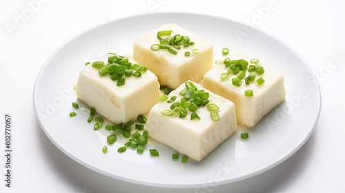 White tofu with sliced spring onions on a plate isolated on white background.