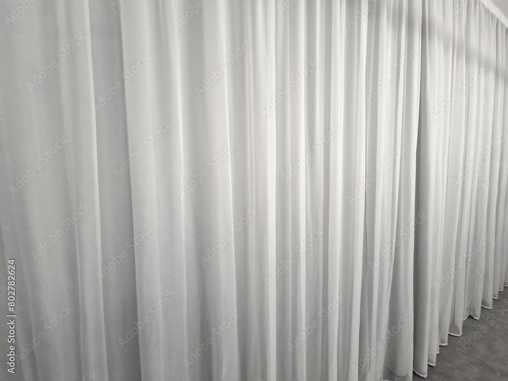 Obraz premium the curtain hangs from the ceiling to the floor. smooth satin synthetic curtain dividing the space and forming a soft textile background. weights at the bottom of the edge of the fabric