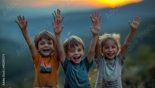 Silhouette of happy children standing with raised hands on the mountain 
