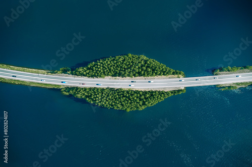 Aerial view of road through blue lake or sea with green woods in Finland.