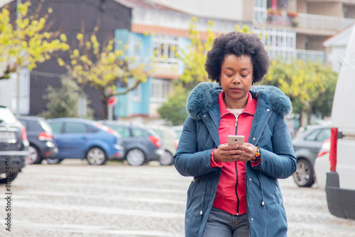 afro woman with mobile phone on the street