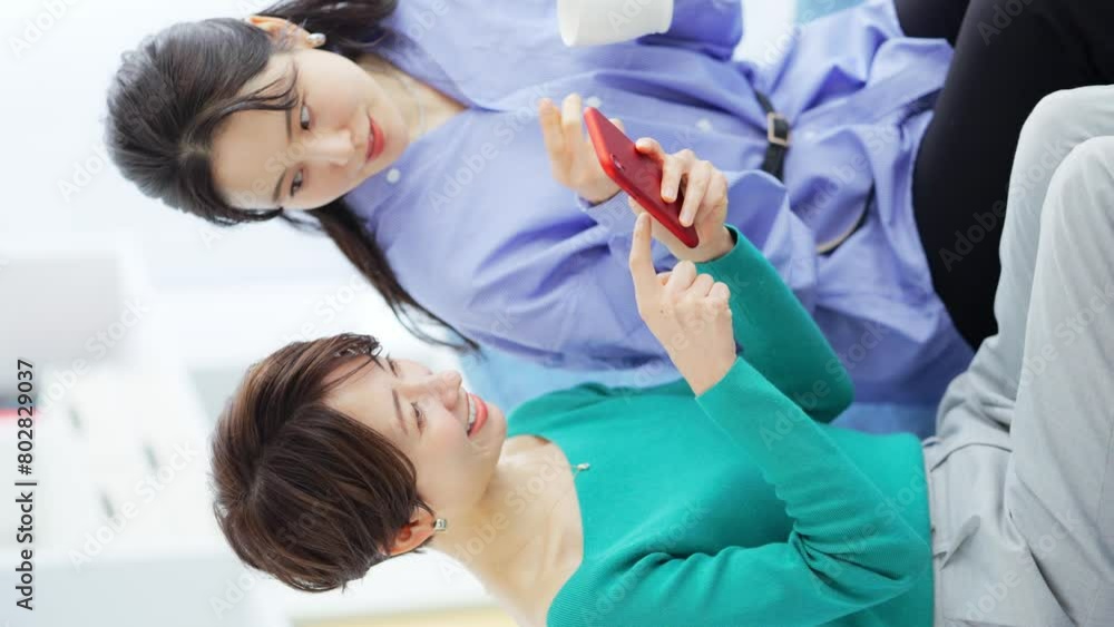 スマホを見る女性とカップを持つ女性 スマホを見る女性とカップを持つ女性