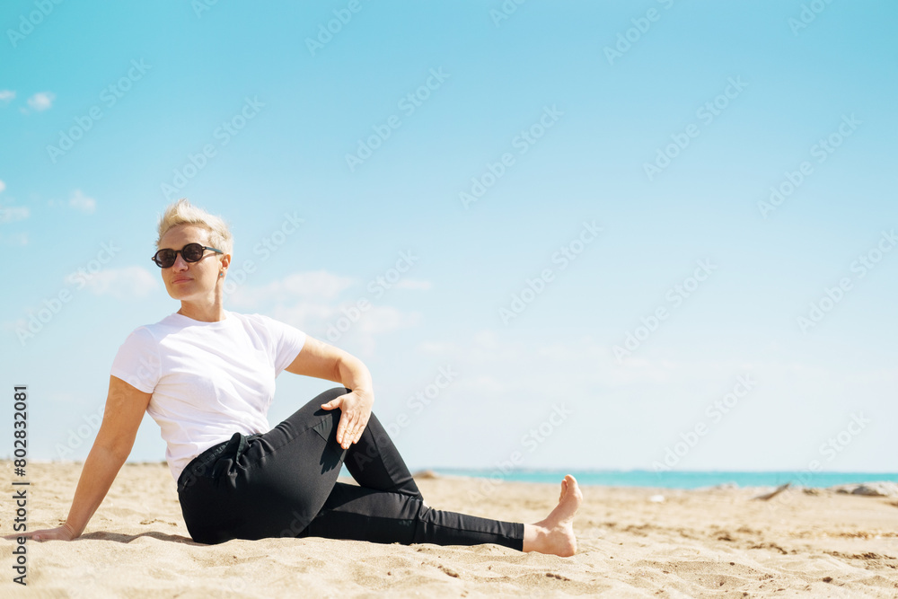 Middle Aged Female Doing Spinal Twist Yoga Exercises. Mindfulness Zen Spiritual Meditation Tips. Kundalini Yoga. Reiki Meditation. Relaxing. Unity With Nature. Sea or Ocean Coast Beach Middle Aged Female Doing Spinal Twist Yoga Exercises. Mindfulness Zen Spiritual Meditation Tips. Kundalini Yoga. Reiki Meditation. Relaxing. Unity With Nature. Sea or Ocean Coast Beach