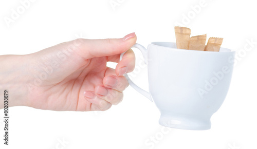 Sugar sticks in hand and white cup on white background isolation