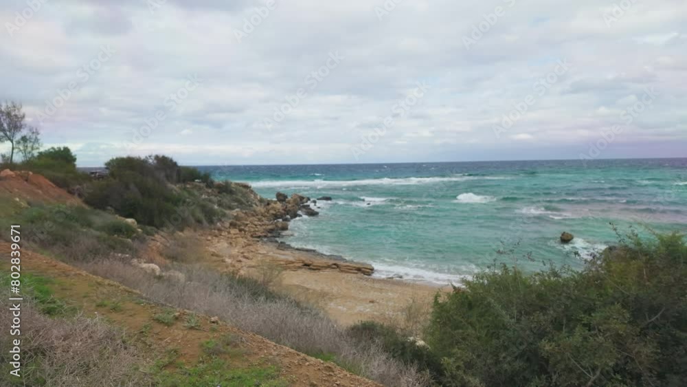 serene coastal landscape in Cyprus. A rugged coastline with a mix of sandy patches and rocky outcrops edges up to the turquoise waters of the Mediterranean. serene coastal landscape in Cyprus. A rugged coastline with a mix of sandy patches and rocky outcrops edges up to the turquoise waters of the Mediterranean.