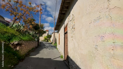 Wallpaper Mural A sunlit alley in Lefkara, flanked by traditional whitewashed walls, an aged wooden door, and a blooming tree, evoking the village's rustic charm. Torontodigital.ca