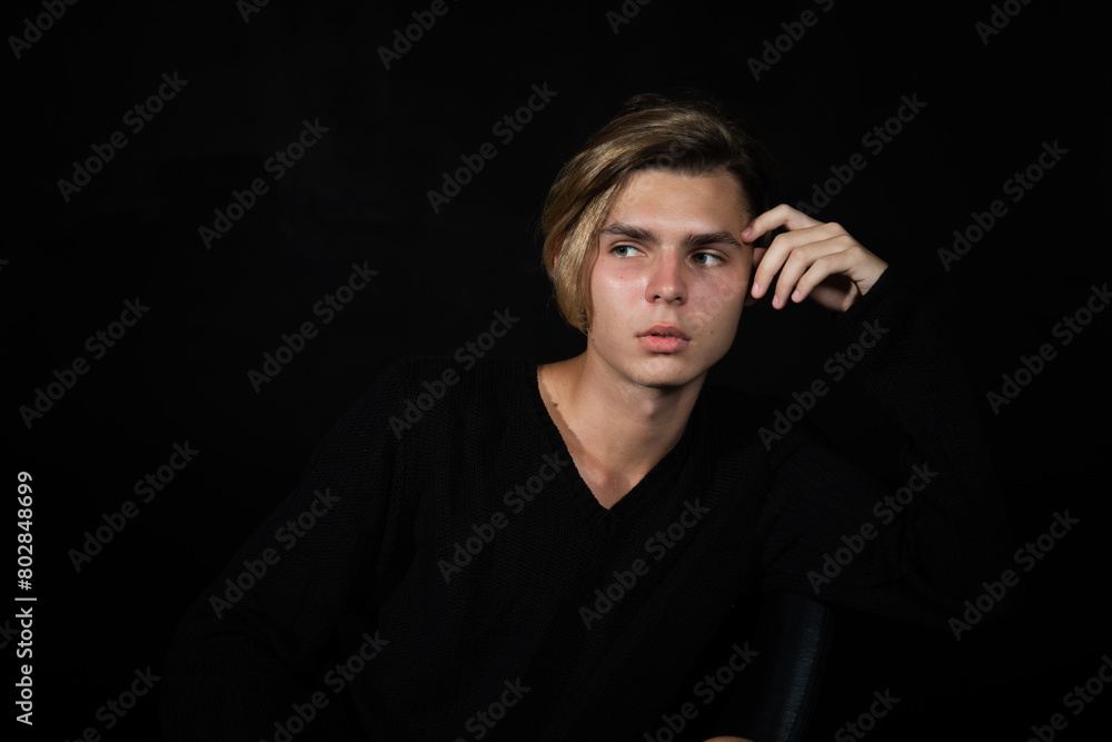 A young attractive guy is resting. Black background. A young attractive guy is resting. Black background.