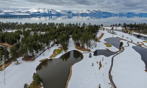 Golf course covered in snow, moutains and forest and calm Lake Tahoe. Stateline, Nevada, United States of America.