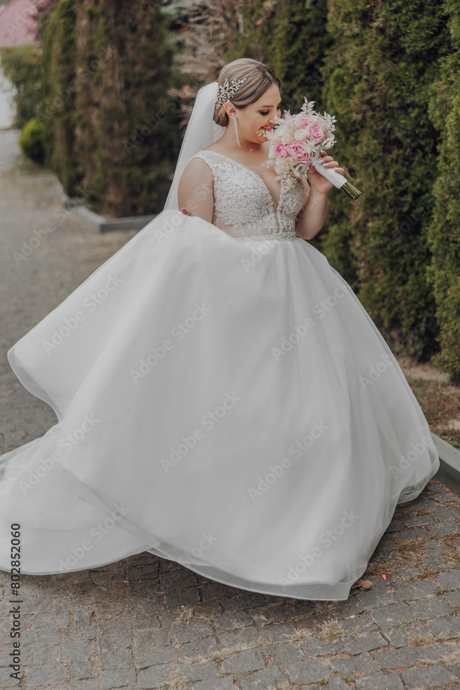 A woman in a white wedding dress is walking down a street holding a bouquet of pink flowers A woman in a white wedding dress is walking down a street holding a bouquet of pink flowers