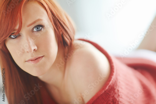 Woman, portrait and redhair with closeup in bedroom with makeup for beauty with blue eyes in morning. Expression, comfort and relax in sweater for winter with confidence in house or apartment photo