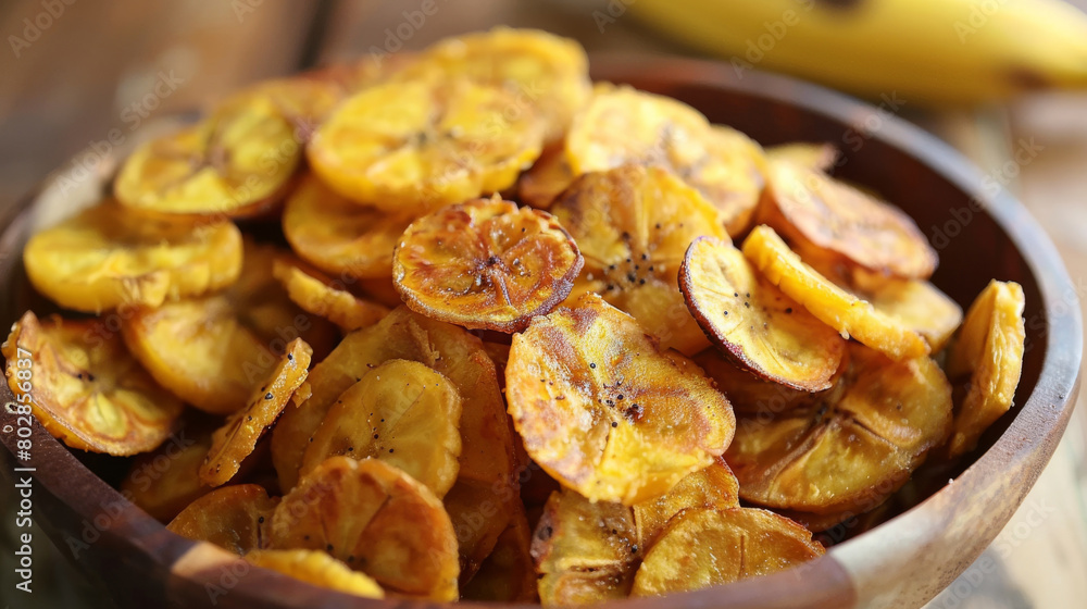 Close-up view of traditional jamaican snack cuisine: golden fried plantain chips in a rustic wooden bowl Close-up view of traditional jamaican snack cuisine: golden fried plantain chips in a rustic wooden bowl