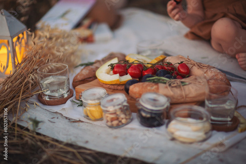 a picnic in a field at sunset. Picnic at the park. Fresh fruits, bread, jam and vegetables on a hot summer day. Picnic lunch. © Cristina