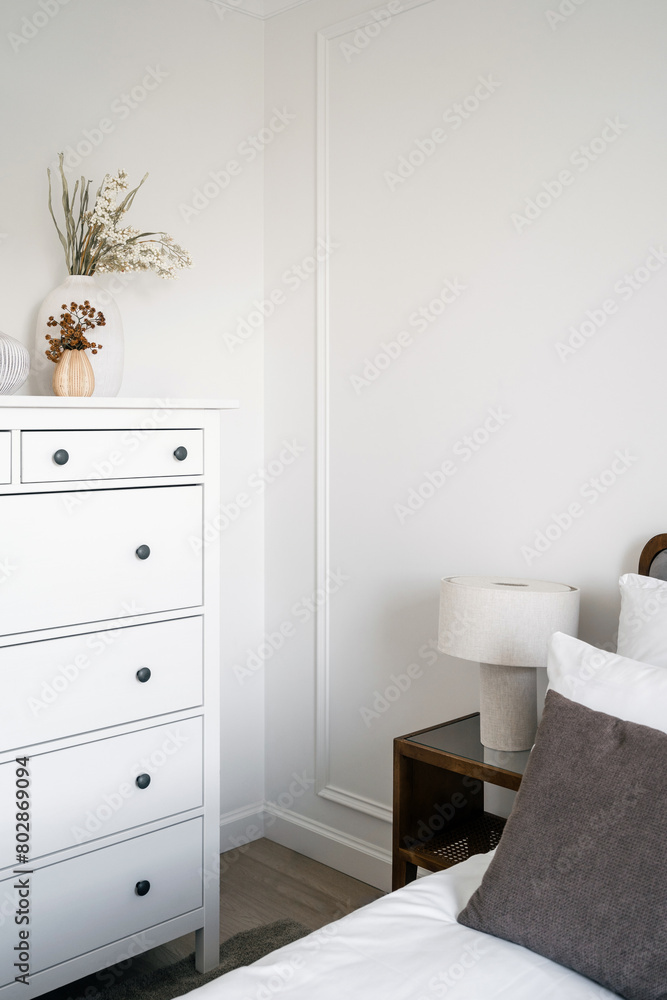 Bedroom with white chest of drawers near comfort bed with lamp on side table Bedroom with white chest of drawers near comfort bed with lamp on side table