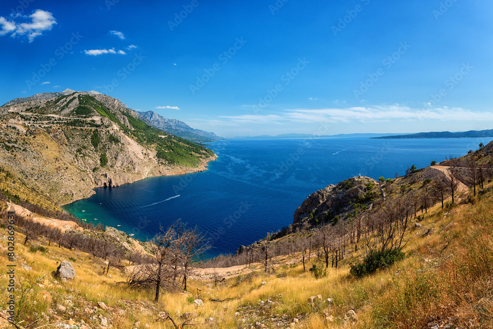 Obraz premium Panoramic view of the Adriatic seacoast surrounded by Dinara mountains, Dalmatia, Croatia. Scenic landscape with sea, rocks and blue sky, outdoor travel background