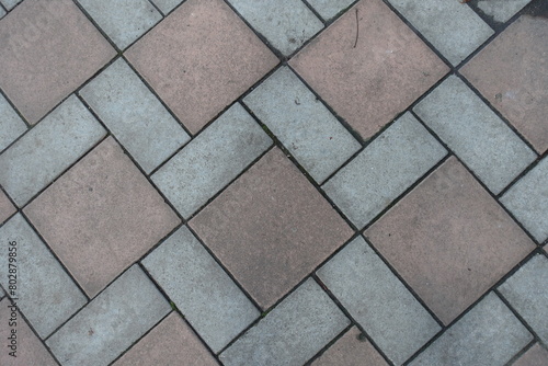 Dusty surface of geometric pavement made of grey and brown concrete tiles