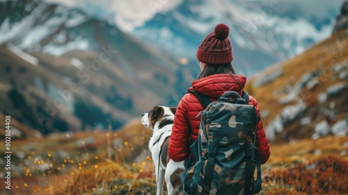 girl in red jacket and red beanie hiking with dog in mountains photo
