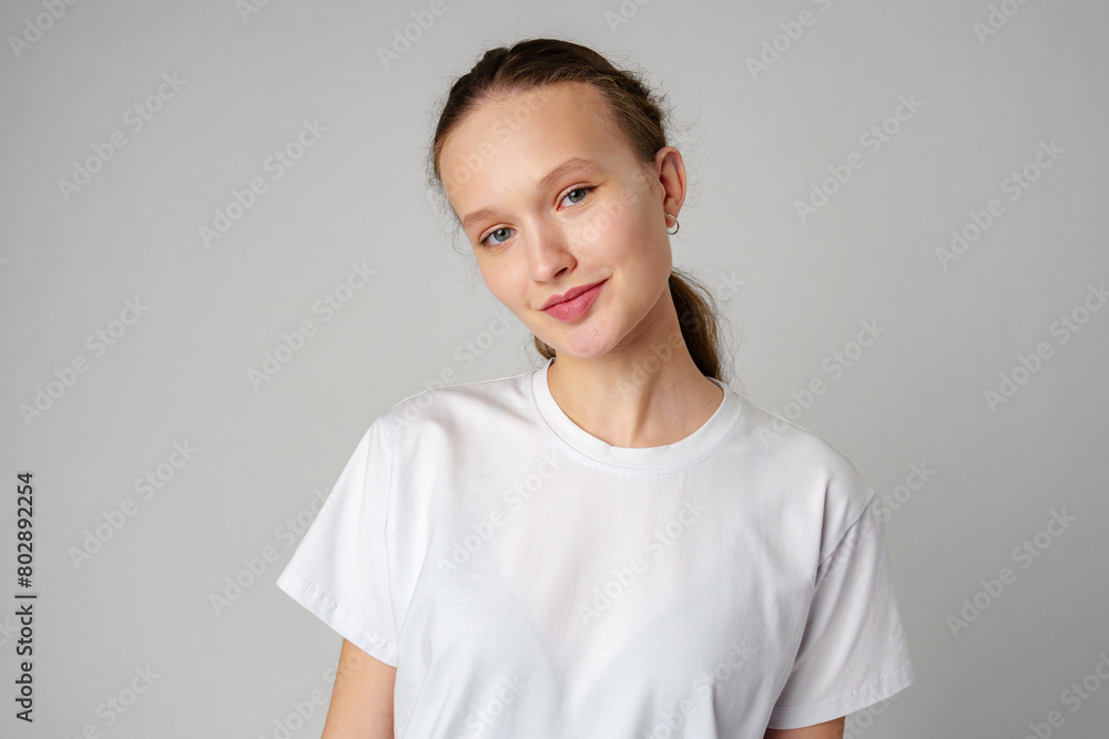 Beautiful young girl posing in white T-shirt and jeans on gray background Beautiful young girl posing in white T-shirt and jeans on gray background