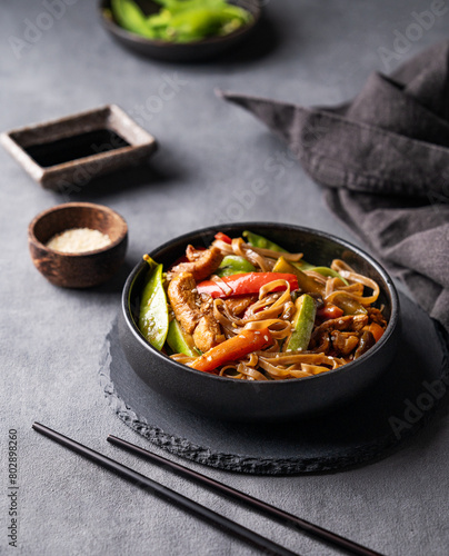 Stir-fry with soba noodles, meat and vegetables on dark background with napkin. Asian fast and healthy food concept photo