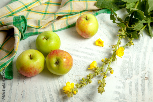 Several green apples on white wooden background..