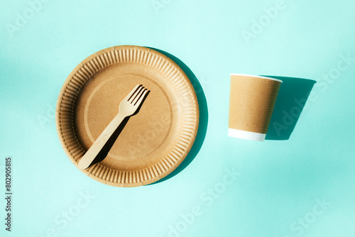 A paper utensils, plates and wooden cutlery on a blue background. Eco friendly pattern, zero waste concept. Top view