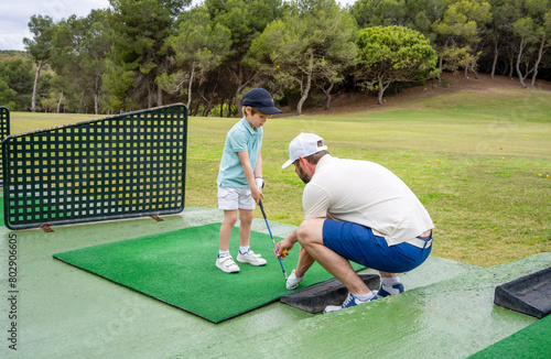 Dad teaches his little son to play golf.