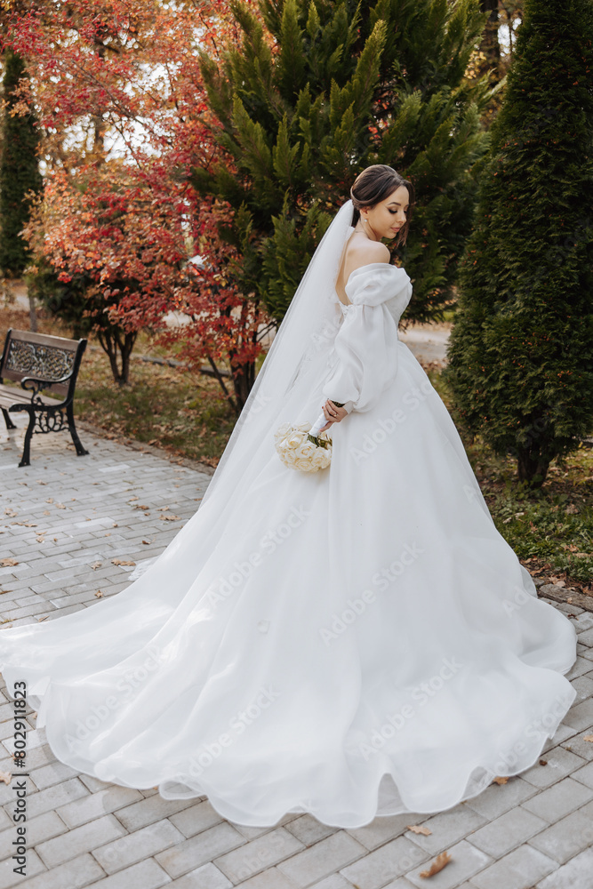 A woman in a white dress is standing in front of a bench. She is holding a bouquet of flowers A woman in a white dress is standing in front of a bench. She is holding a bouquet of flowers