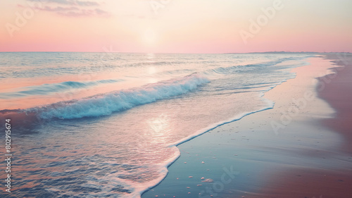 Soft pink sunrise over a serene beach with gentle waves washing ashore, creating a tranquil and picturesque setting.