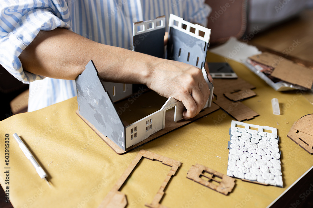 A girl assembles a model of a building from thick cardboard.