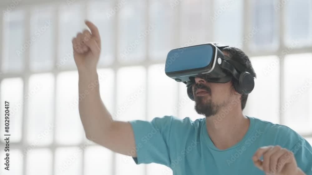 Young man using virtual reality glasses with controllers, playing video games, gamer wearing new generation gaming headset for entertainment and education at home, future technology concept. High Young man using virtual reality glasses with controllers, playing video games, gamer wearing new generation gaming headset for entertainment and education at home, future technology concept. High