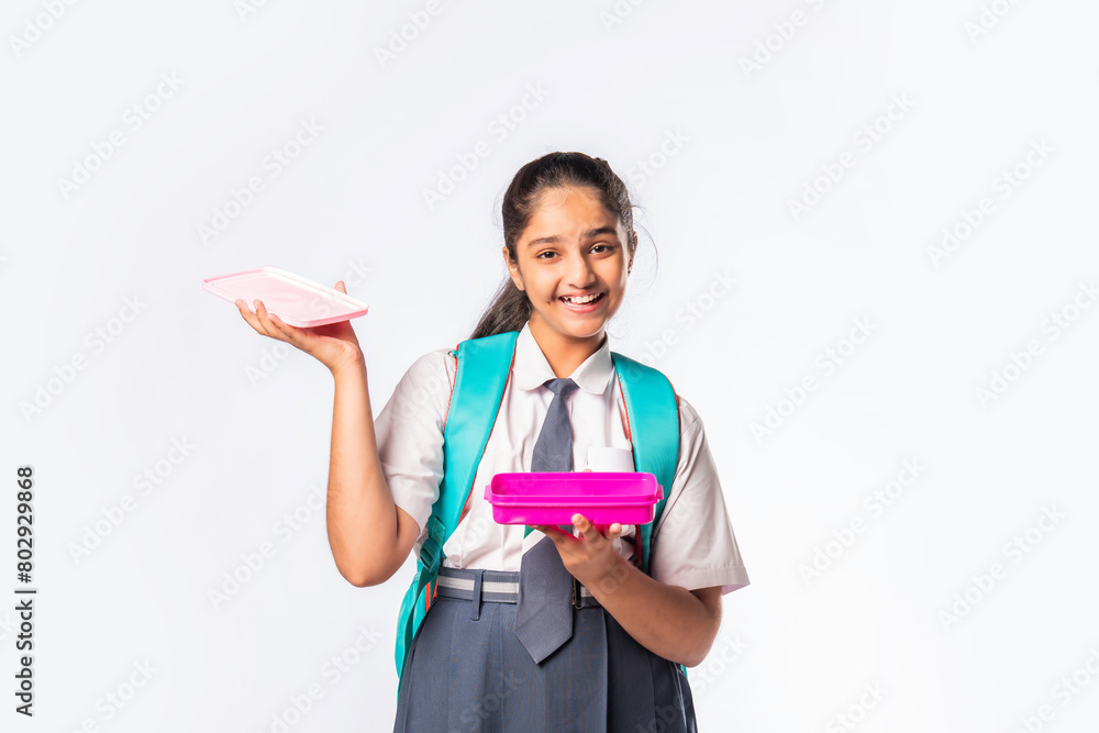 Healthy nutrition for kids - Indian asian female school child in school uniform holding a tiffin lunch box Healthy nutrition for kids - Indian asian female school child in school uniform holding a tiffin lunch box