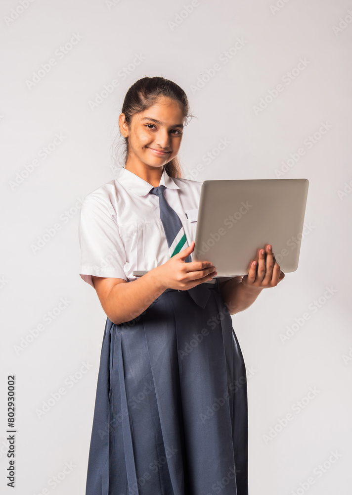 Indian asian schoolgirl in school uniform holding laptop isolated on white background Indian asian schoolgirl in school uniform holding laptop isolated on white background