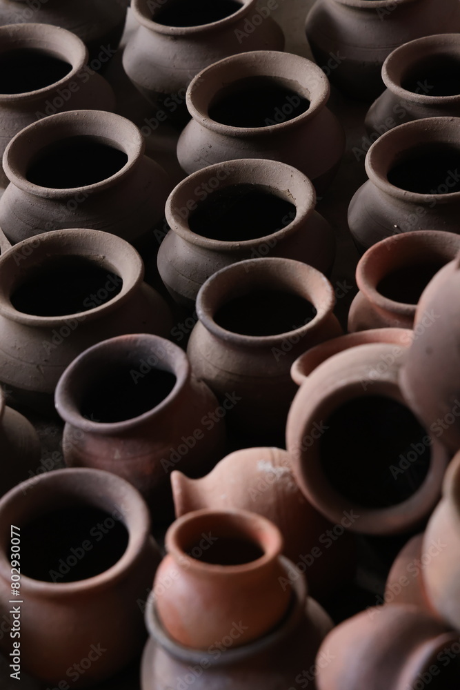pots are gathered and arranged in a pattern in the empty space. The potter works on a pottery wheel to made of soft colored clay, retro style toned Clay pots with hand and equipment pots are gathered and arranged in a pattern in the empty space. The potter works on a pottery wheel to made of soft colored clay, retro style toned Clay pots with hand and equipment