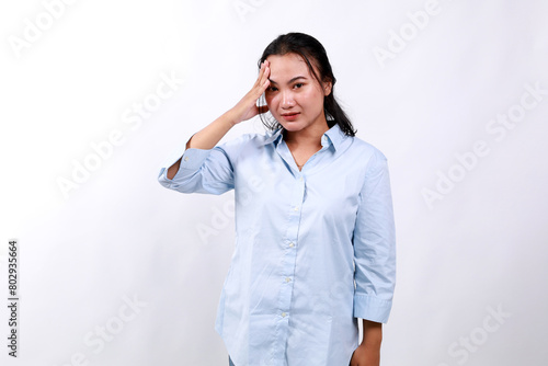Bothered and tired asian woman, looking complicated, touching forehead, face palm sign, looking distressed at camera, white background