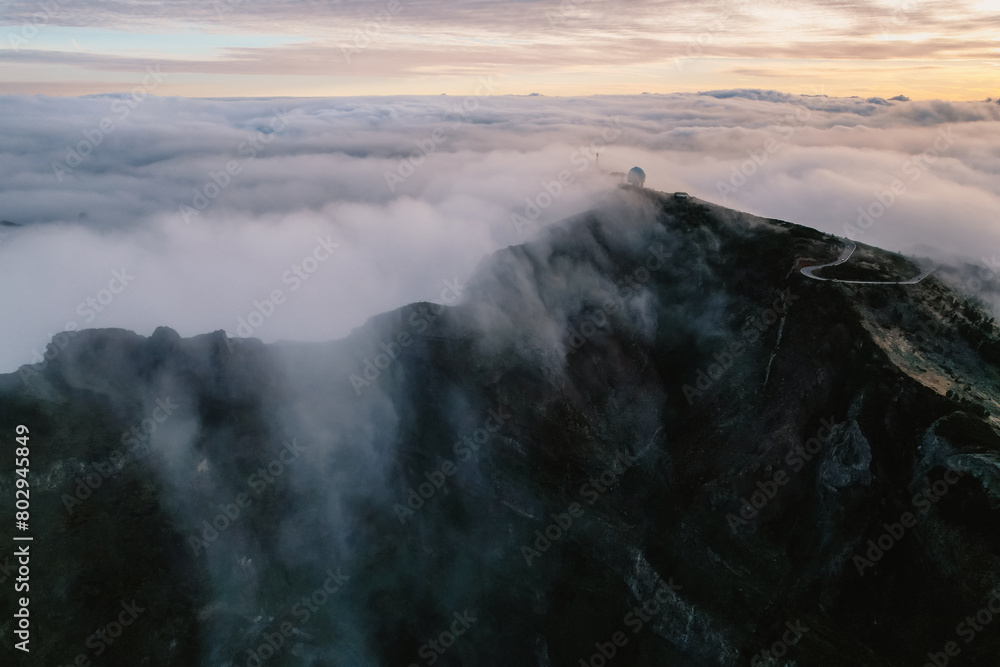 Aerial view of majestic mountain ridges at sunrise with falling fog from top of Pico do Areeiro, Madeira island, Portugal