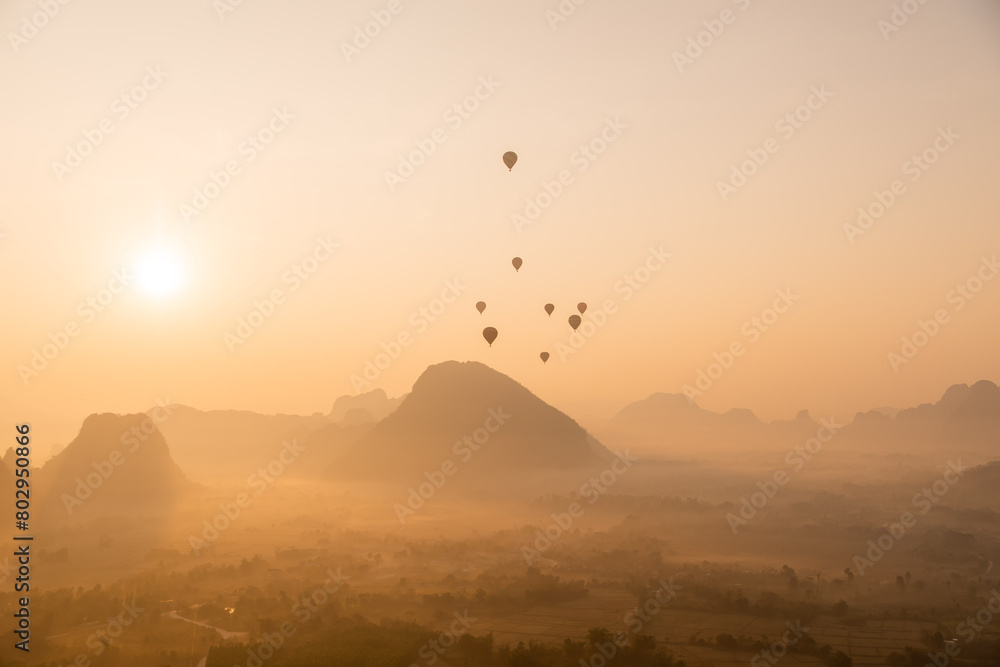 hot air balloons rising at golden sunrise in the mountain valley in Vang Vieng, the adventure capital of Laos
