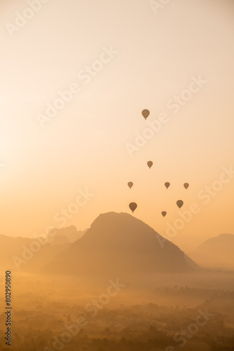 hot air balloons rising at golden sunrise in the mountain valley in Vang Vieng, the adventure capital of Laos