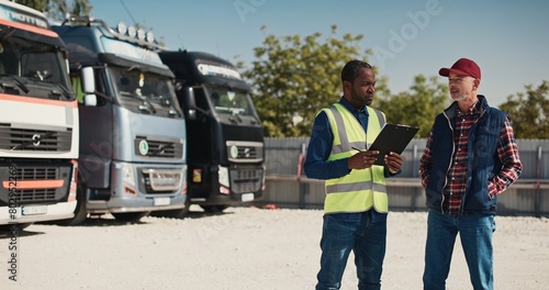 Foto Hardworking mixed-race people discussing about upcoming import goods on their trucks