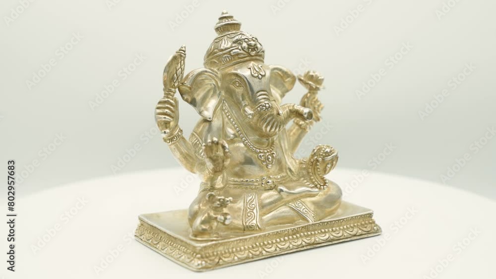 Silver manufactured sculpture of indian hindu god Ganesha, the elephant with four arms and the small mouse next to him, with beautiful decorations and all the classic religious references Silver manufactured sculpture of indian hindu god Ganesha, the elephant with four arms and the small mouse next to him, with beautiful decorations and all the classic religious references
