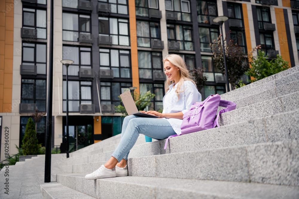Full body length photo of young cheerful smiling student woman sitting stairs learning management bachelor program using laptop outdoors Full body length photo of young cheerful smiling student woman sitting stairs learning management bachelor program using laptop outdoors