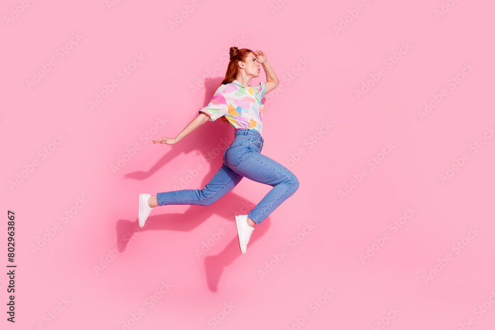 Full body length photo of red hair funky hipster curious looking far away jumping air trampoline isolated on pink color background