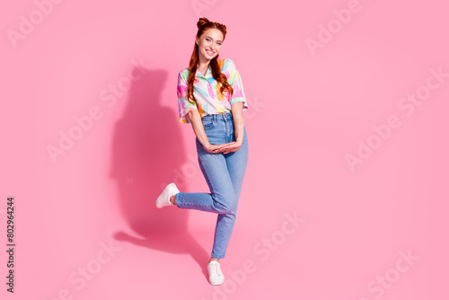 Full size photo of adorable girl dressed colorful blouse jeans pants standing look at sale empty space isolated on pink color background