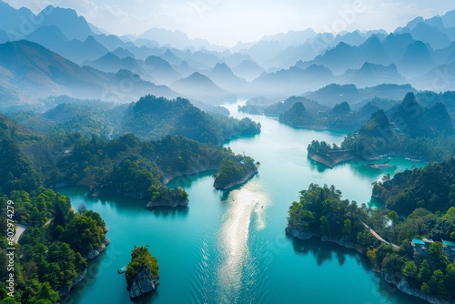 Wallpaper Mural An aerial view of a lake in the mountains. The water is a vibrant blue and the sky is hazy. The mountains are covered in lush green trees. Torontodigital.ca