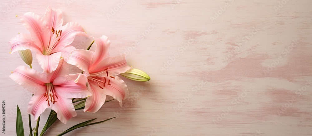 A copy space image features two pink day lilies resting on a textured tan ceramic tile A copy space image features two pink day lilies resting on a textured tan ceramic tile