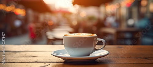 A cup of coffee sits on a table against a blurred cafe background creating a copy space image