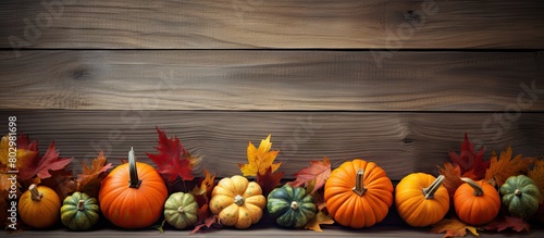 A copy space image featuring autumn leaves and pumpkins arranged on an old wooden background