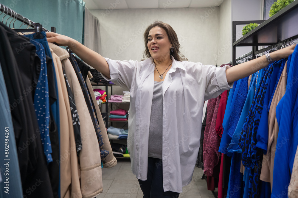 A fat woman chooses clothes in a plus size store. A fat woman chooses clothes in a plus size store.